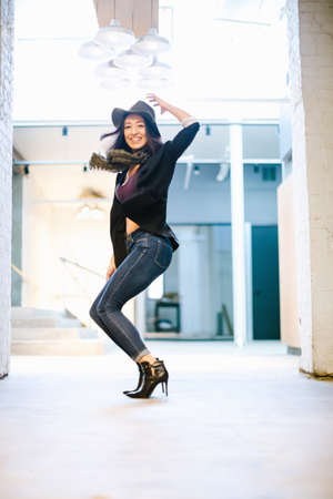 Young woman posing, knees bent, in front of buildingの写真素材