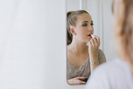 Mirror image of young woman applying lipstickの写真素材