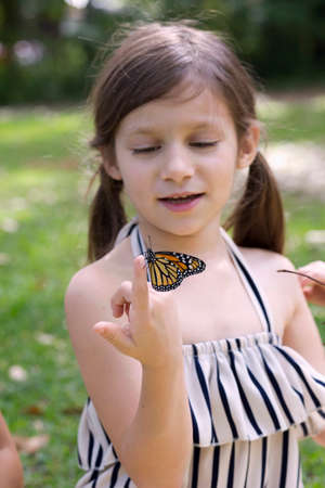 Girl holding monarch butterfly on fingerの写真素材
