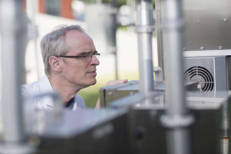 Male meteorologist texting on smartphone at outdoor weather station equipment