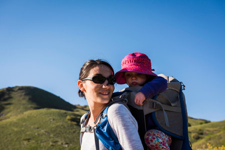 Mother carrying young daughter on back, hiking the Bonneville Shoreline Trail in the Wasatch Foothills above Salt Lake City, Utah, USAの写真素材