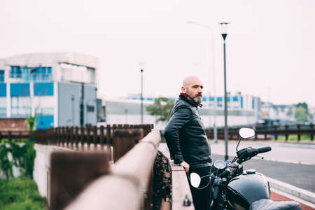 Mature male motorcyclist watching from roadsideの写真素材