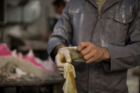 Cropped view of sculptor in artists' studio removing latex gloves