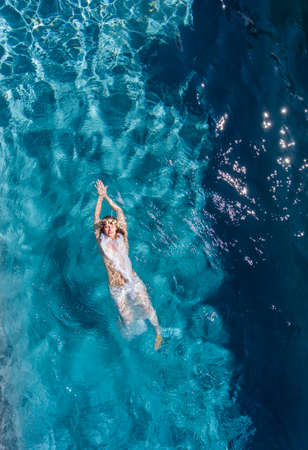 Overhead view of woman swimming on back in swimming poolの写真素材