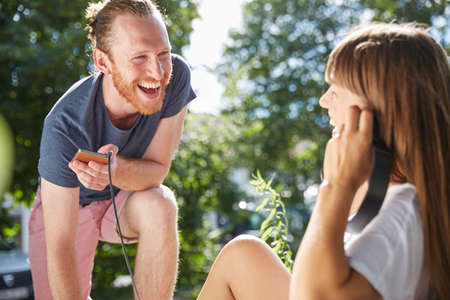 Young couple outdoors, listening to music through earphones