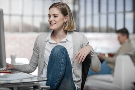 Young woman at home, working at desk, smilingの写真素材