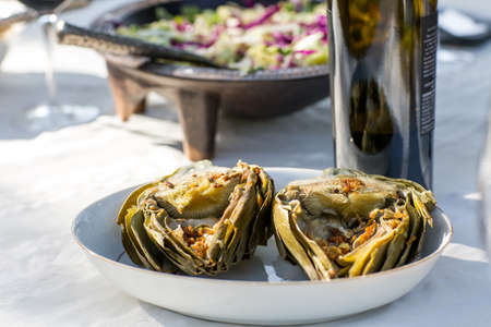 Party garden table with wine bottle and baked artichokesの写真素材