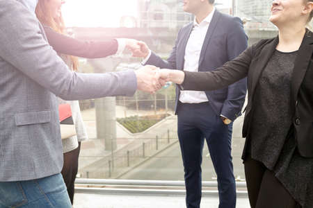 Neck down view businesswomen and men shaking hands on city footbridge, London, UKの写真素材