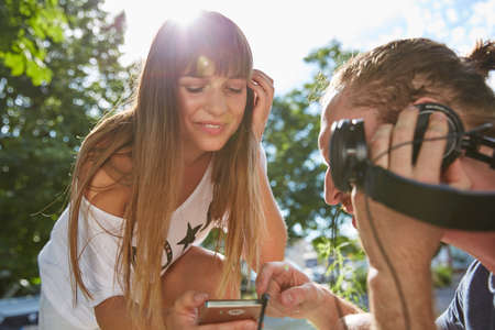Young couple outdoors, listening to music through headphonesの写真素材