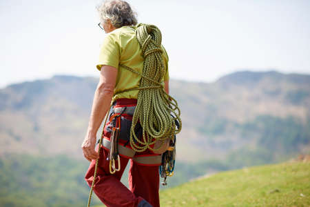 Rear view of rock climber carrying climbing rope on backの写真素材