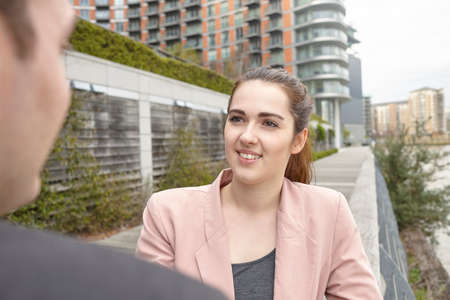 Young businesswoman and man having discussion on waterfront, London, UK