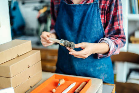 Detail of hands holding paintbrush in book arts studio