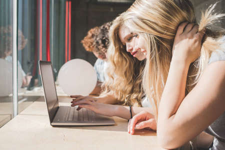 Co-workers working on laptop beside bar counter by windowの写真素材