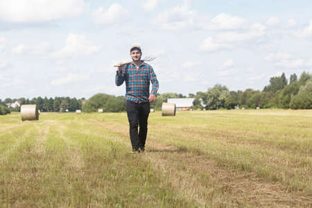 Farmer in field carrying spade on shoulderの写真素材