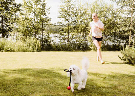 Woman running after coton de tulear dog in garden, Orivesi, Finlandの写真素材