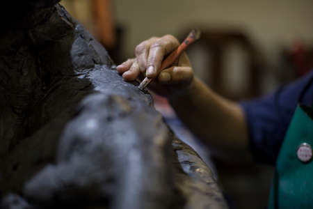 Cropped view of sculptor in artists' studio creating sculpture with hand toolの写真素材