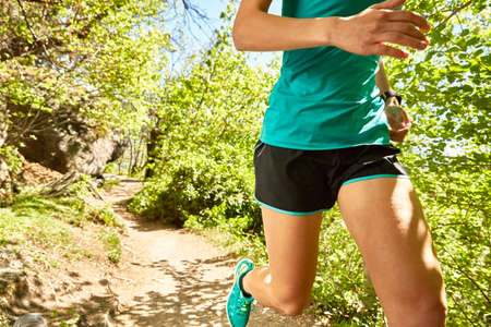 Young woman running along rural pathway, mid section, Meran, South Tyrol, Italy