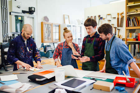 Group of young craftspeople using digital tablet in book arts workshop
