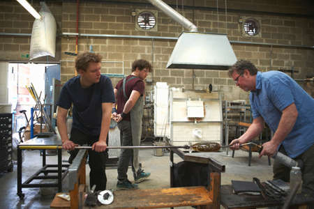 Glassblowers in workshop using blowtorch