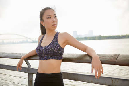 Woman wearing crop top by river looking away, South Bund, Shanghai, China