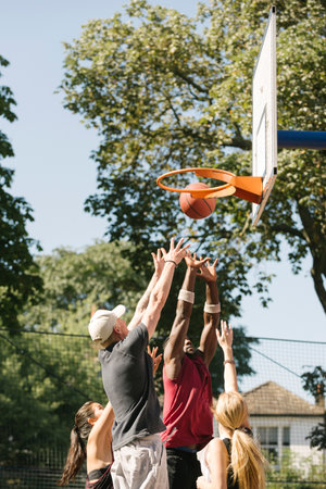 Female and male basketball players throwing ball at basketball hoop
