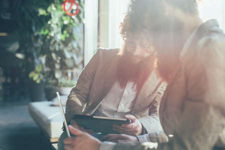 Male adult hipster twins working on digital tablet and laptop in office