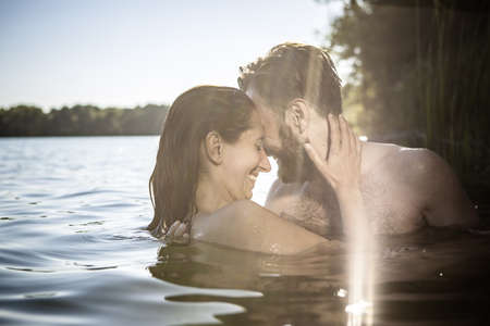 Couple face to face hugging, smiling in water, Berlin, Germanyの写真素材