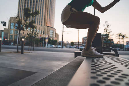 Young woman exercising outdoors, stepping up onto benchの写真素材