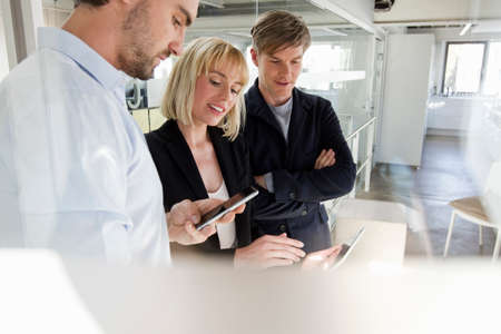 Colleagues in office looking at smartphone