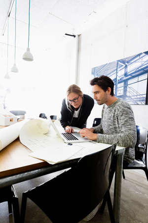 Colleagues in conference room using laptopの写真素材