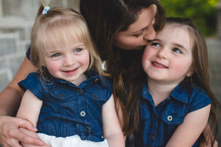 Girls sitting on mother's lap smilingの写真素材