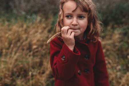 Portrait of girl chewing long grass in field