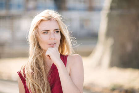 Portrait of pretty young woman with long blond hair in parkの写真素材