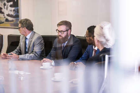 Window view of businesswoman and businessmen in board meetingの写真素材
