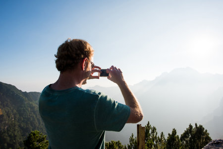 Rear view of man taking photograph of mountains, Passo Maniva, Italyの写真素材