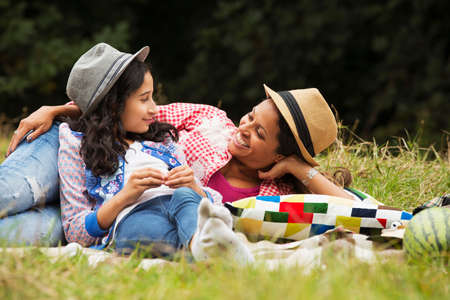 Mother and daughter relaxing outdoors, lying on picnic blanketの写真素材