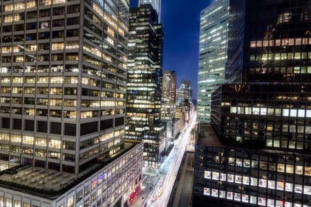 Elevated view of glass fronted skyscrapers illuminated at night, New York, USA