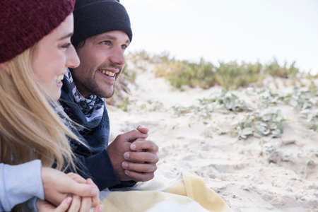 Young couple lying on picnic blanket at beach, Western Cape, South Africa