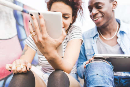 Couple using digital tablets smiling