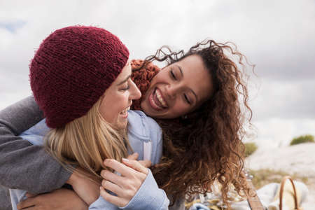 Two young female friends hugging at beach, Western Cape, South Africaの写真素材