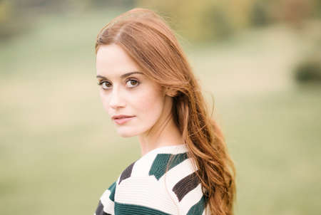 Portrait of red haired woman looking at camera