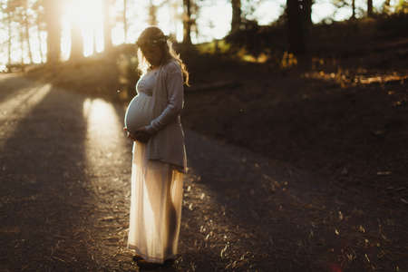 Pregnant woman in sunlight touching stomachの写真素材