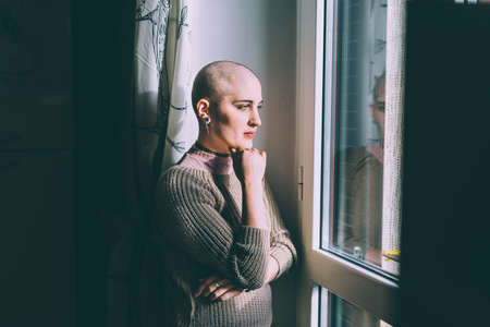 Portrait of young woman with shaved head gazing through window