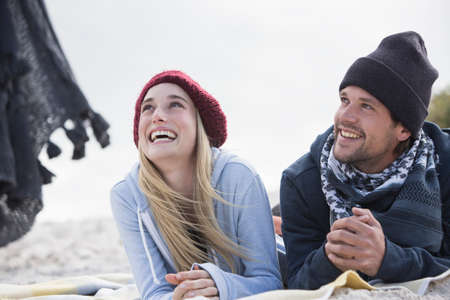 Young couple looking up from picnic blanket at beach, Western Cape, South Africa