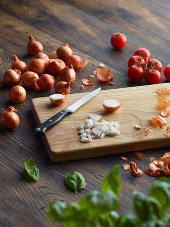 Fresh basil and cherry tomatoes with onions chopped on cutting boardの写真素材