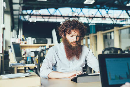 Young male hipster using digital tablet at deskの写真素材