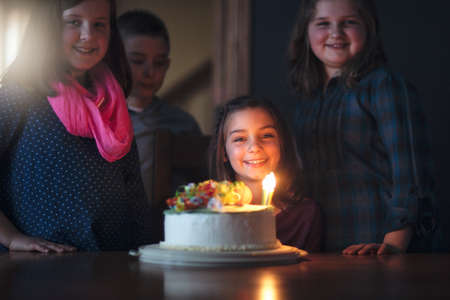 Girl with birthday cake surrounded by friendsの写真素材
