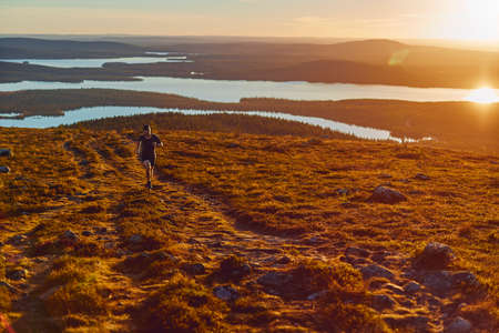 Man trail running on cliff top at sunset, Keimiotunturi, Lapland, Finland