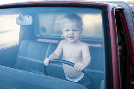 Portrait of male toddler standing in truck holding steering wheelの写真素材