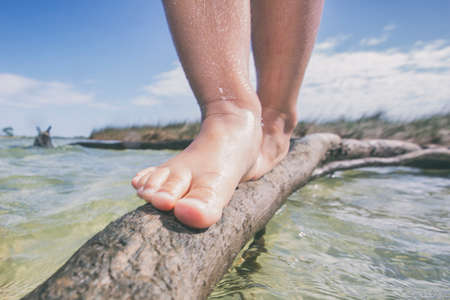 Girl balancing on a branch at beach, low section, Fort Walton Beach, Florida, USA
